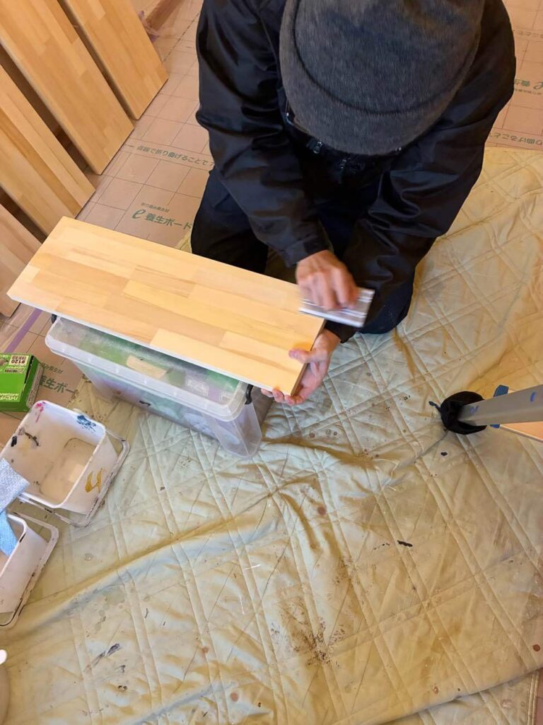 吊戸造作工事に使用しているメルクシパイン集成材は、インドネシア原産のパイン材（松）の小片を接着した木材です。明るい黄色味と穏やかな木目が特徴で、適度な硬さと加工性があり、棚板、カウンター天板、DIY家具の定番素材として人気が高い木材です。節が少なく、反りや曲がりが少ないため、住宅の内装や家具制作に幅広く利用されています。