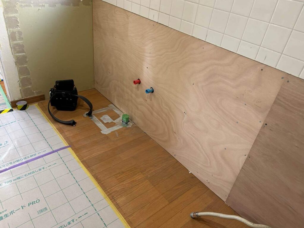 古いキッチンを撤去し、壁の合板下地と給排水配管の切り回しを丁寧に行いました。新しいキッチンを設置するための重要な下準備です。床もしっかり養生し、工事をスムーズに進めていきます。