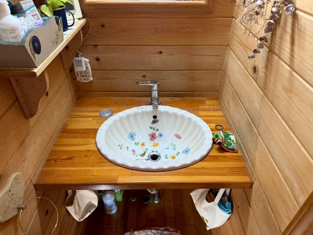 施工前は、木製の造作カウンターに、可愛らしいお花柄の洗面ボウルが設置されていました。とても素敵な空間ですが、水回りのためどうしても木製カウンターの傷みや、収納部分の使い勝手、水はねによる壁への影響が懸念される状態でした。