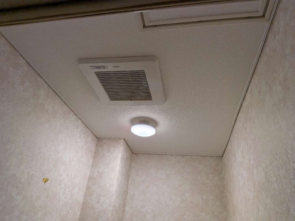 交換後のトイレ天井です。新しい天井埋込形の換気扇を設置し、確実な排気機能を確保しました。照明もLECシーリングタイプへ新しく交換し、空間全体を明るく安全にお使いいただけるようになりました。